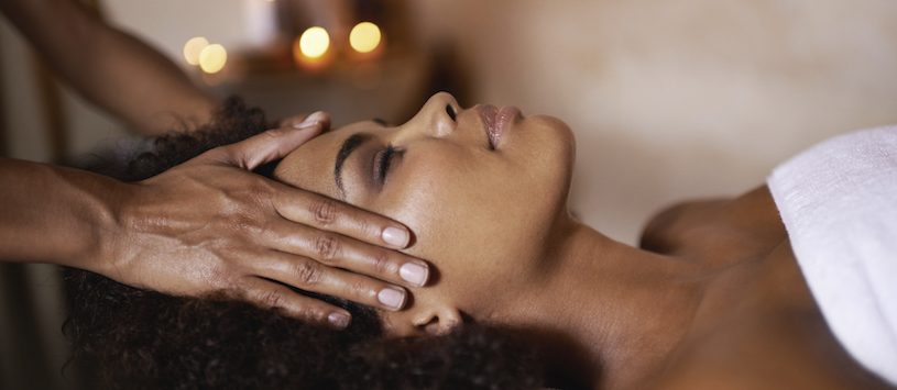 An African American woman getting her temples massaged. If you're interested in Massage Therapy Continuing Education Classes in Williamsville, NY contact us.